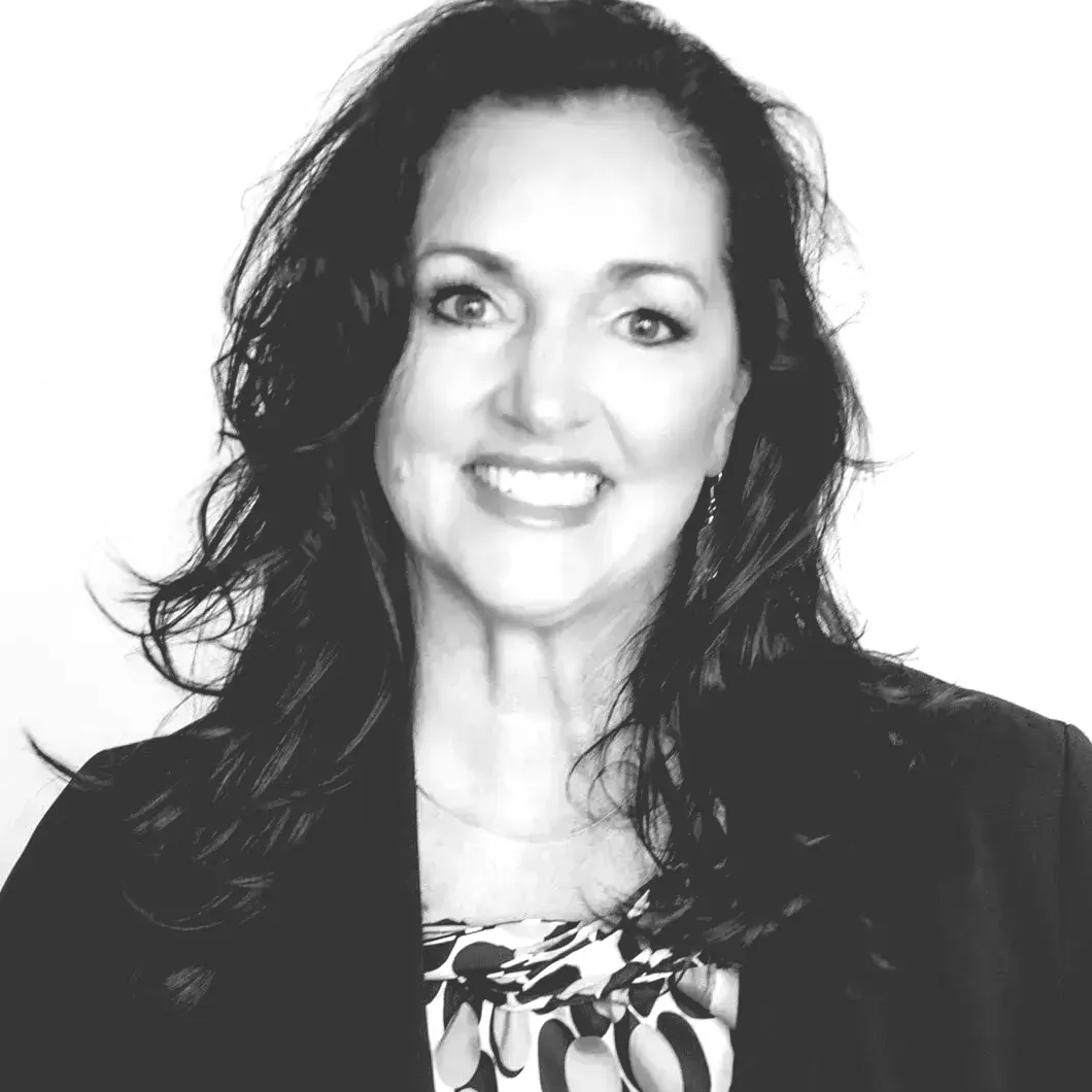 A black and white photo of a woman wearing a jacket and smiling.