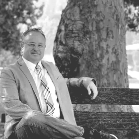 A man in a suit and tie is sitting on a park bench.