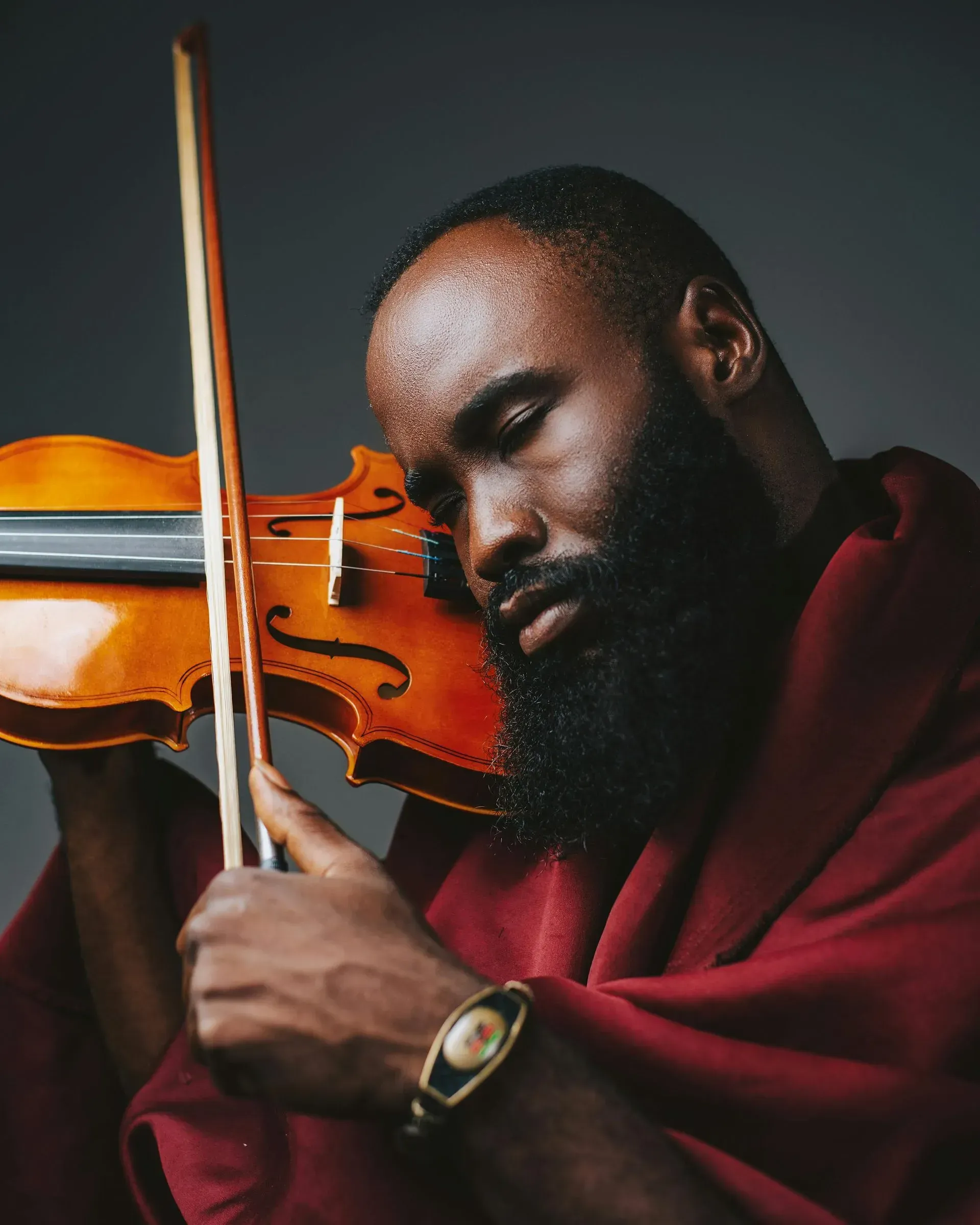 A man with a beard is playing a violin with his eyes closed