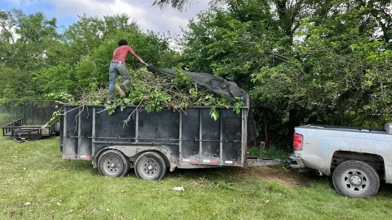 Worker loading brush into dump trailer during land clearing and site prep near Ankeny, Iowa