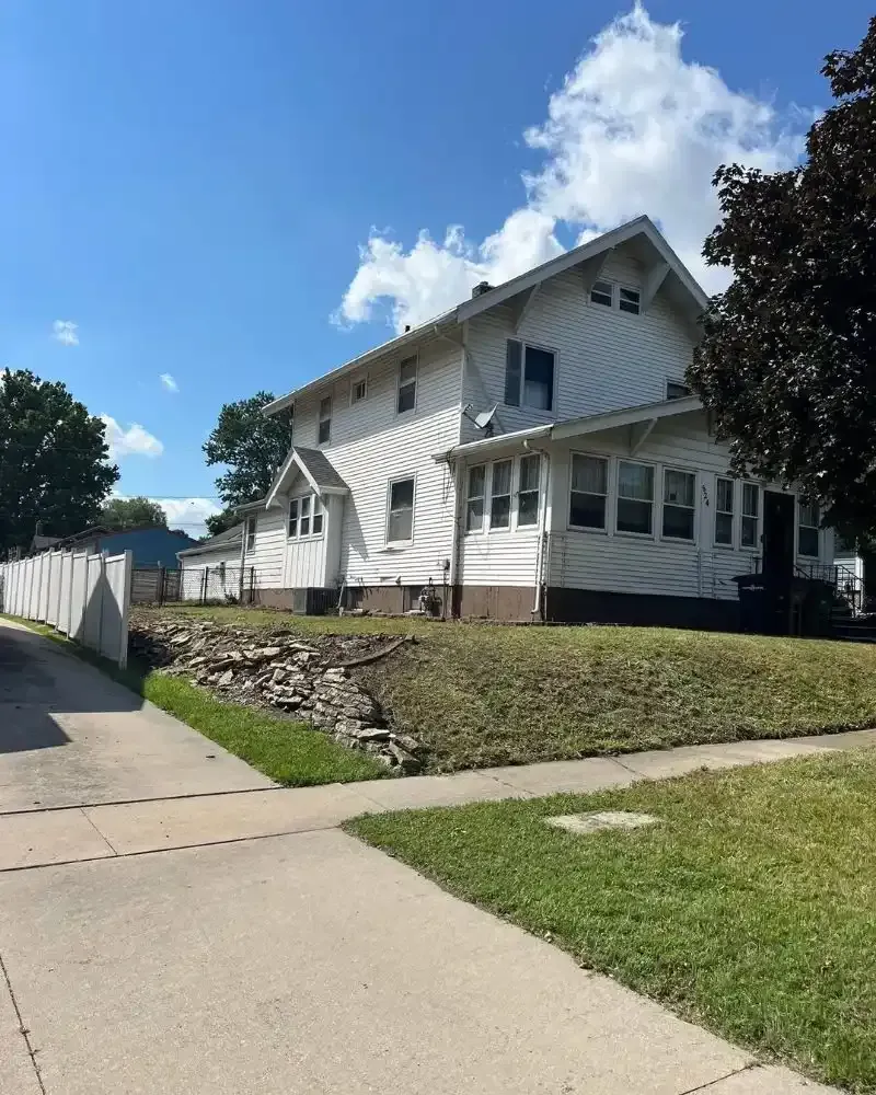 Before-and-after photos of a complete lot cleanup project in Des Moines, IA — brush removal and debris clearing.