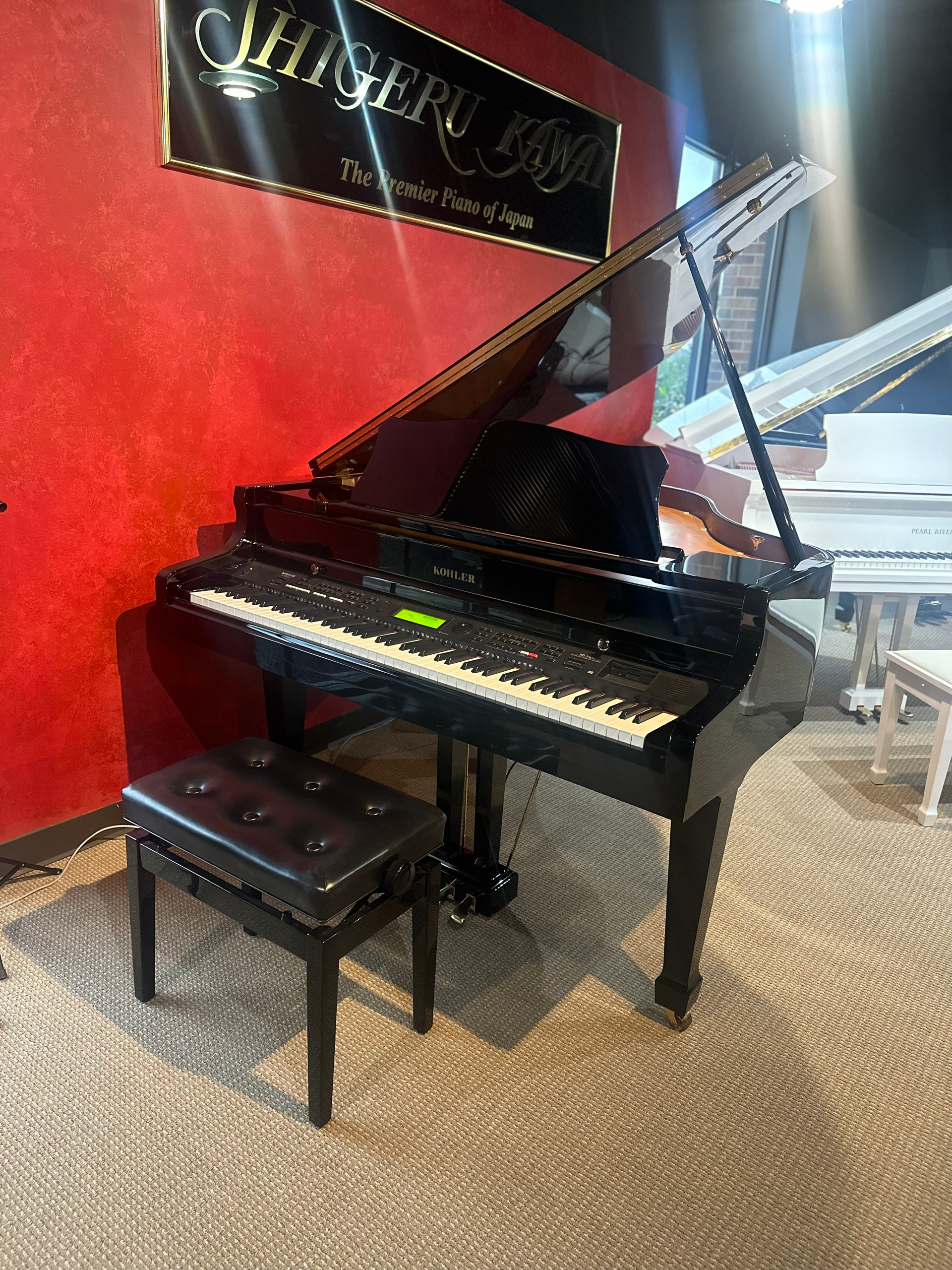 A black grand piano is sitting next to a stool in a room.
