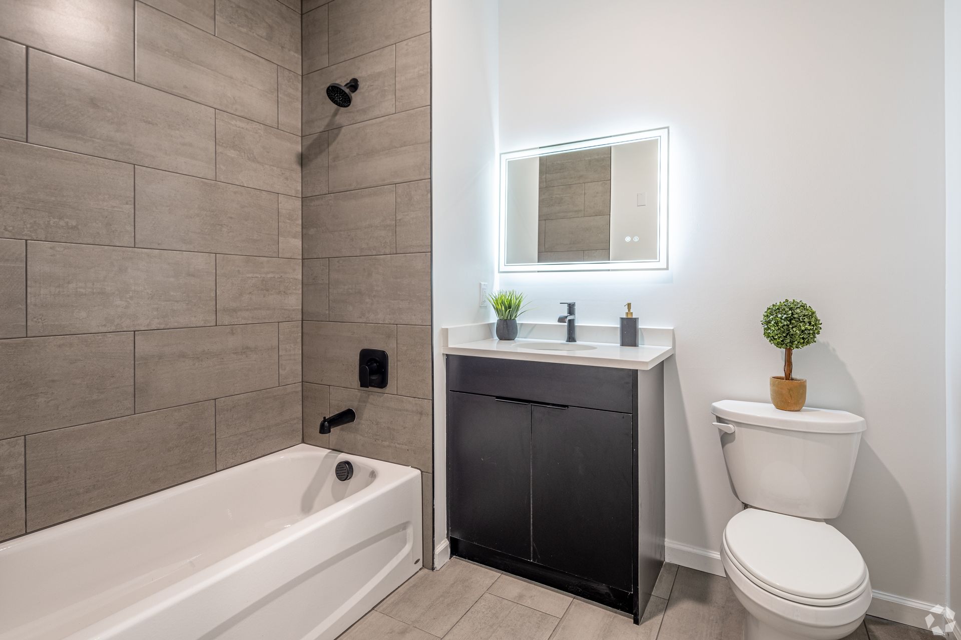 A bathroom with a tub , toilet , sink and mirror.- The Unity