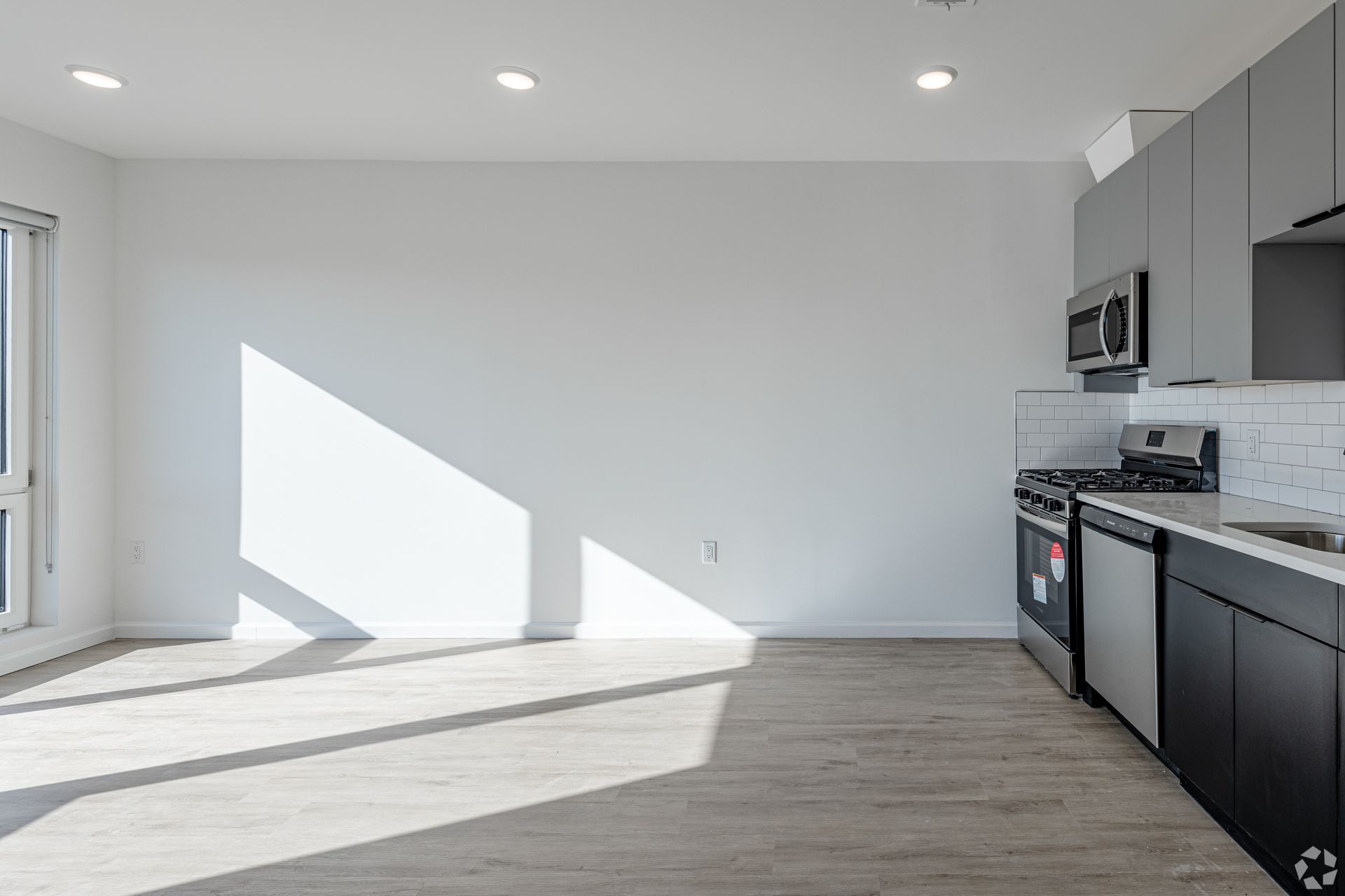 An empty kitchen with a stove , sink , and microwave.- The Unity