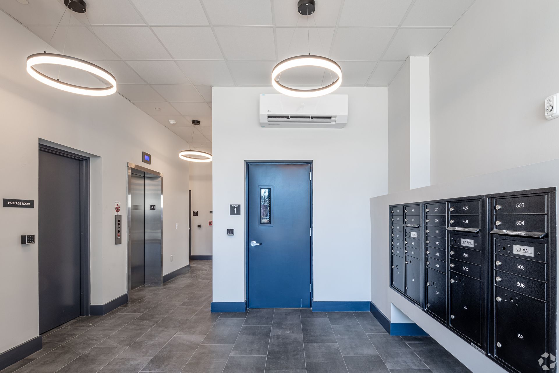 A hallway with elevators and mailboxes in a building- The Unity