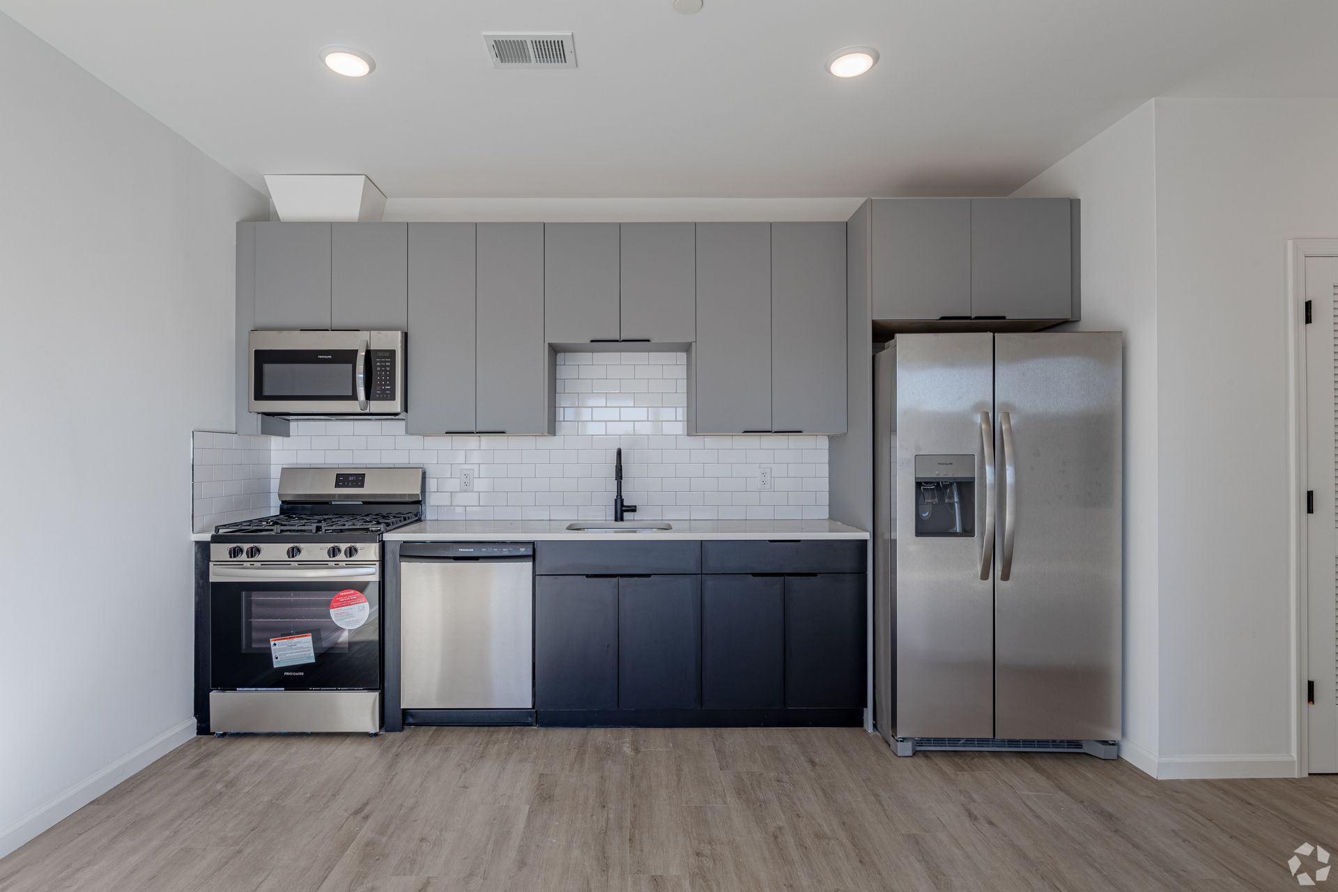 A kitchen with stainless steel appliances and gray cabinets- The Unity