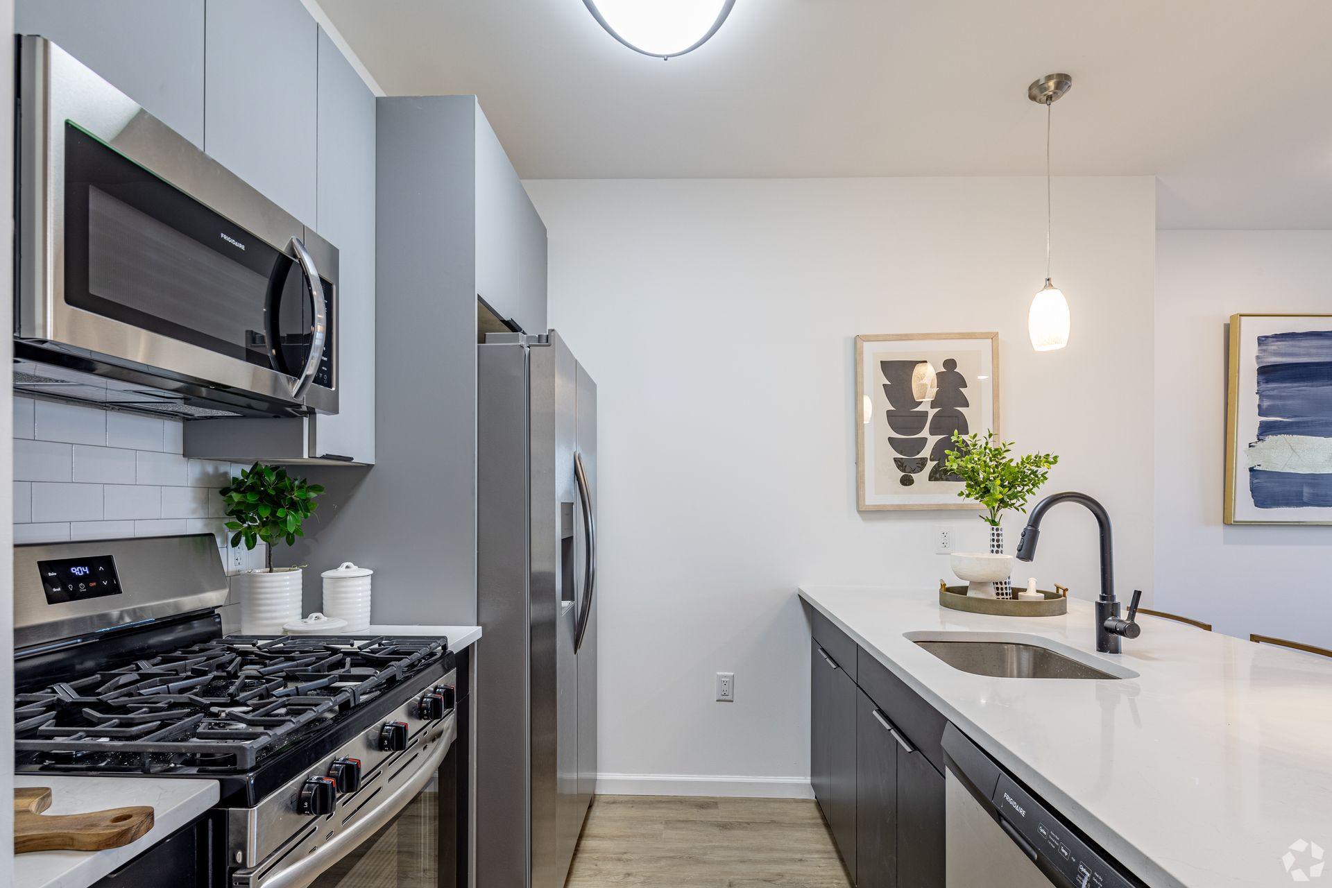 A kitchen with a stove , refrigerator , microwave and sink.- The Unity