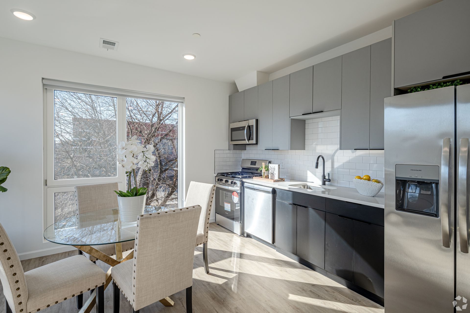 A kitchen with stainless steel appliances and a dining table and chairs.- The Unity