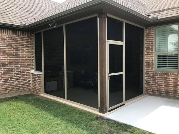 a screened in porch on the side of a brick house