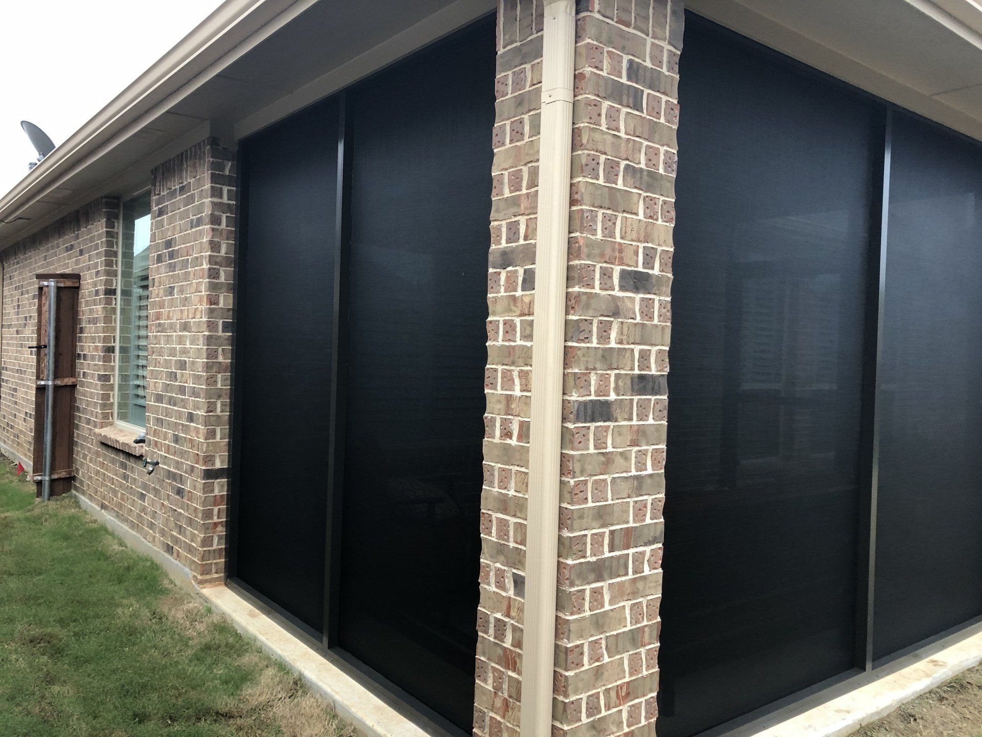 a brick house with a screened in porch with black screens