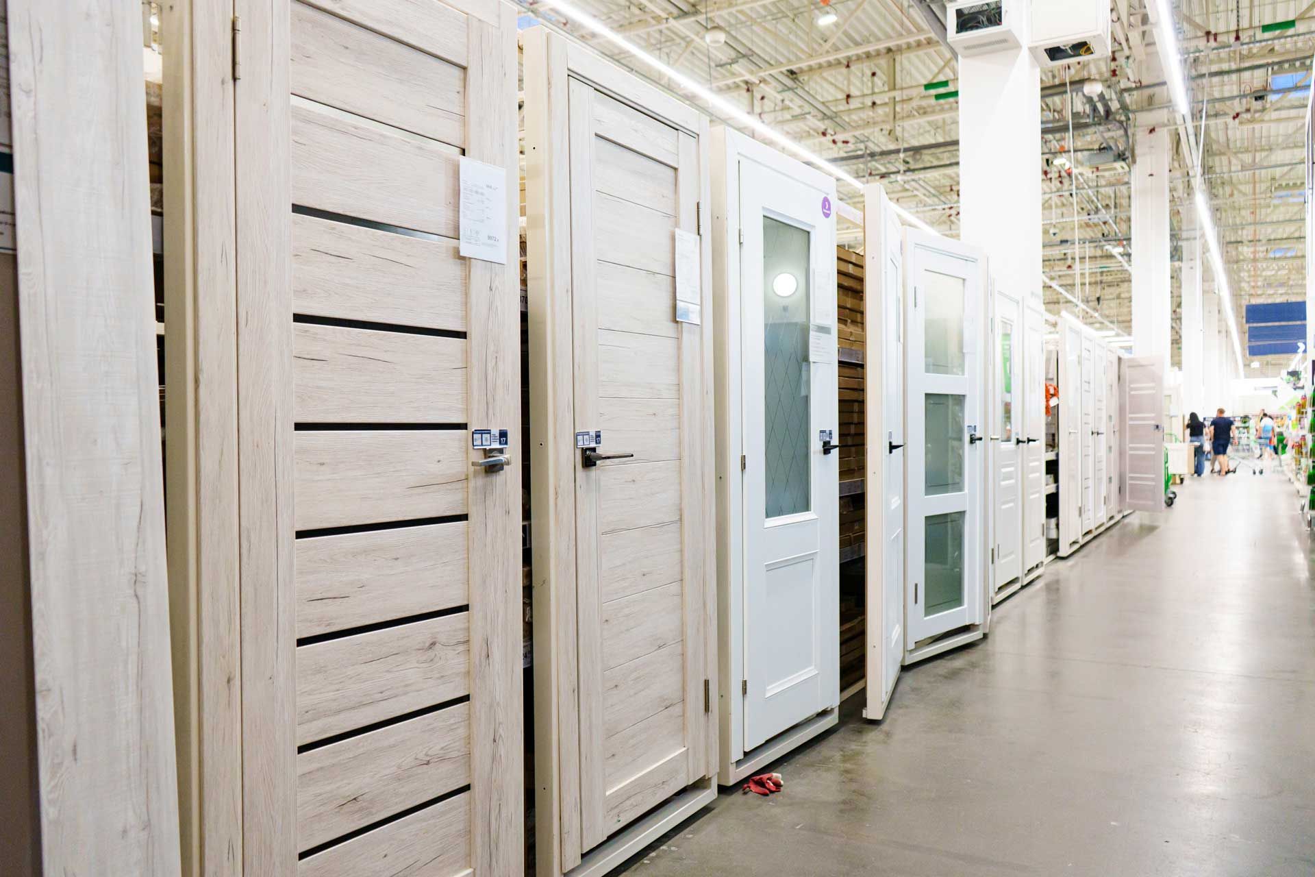 A row of wooden doors are lined up in a store.