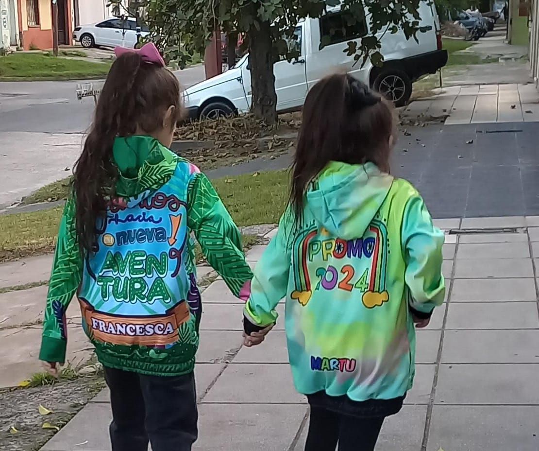 Dos niñas caminan por una acera tomadas de la mano