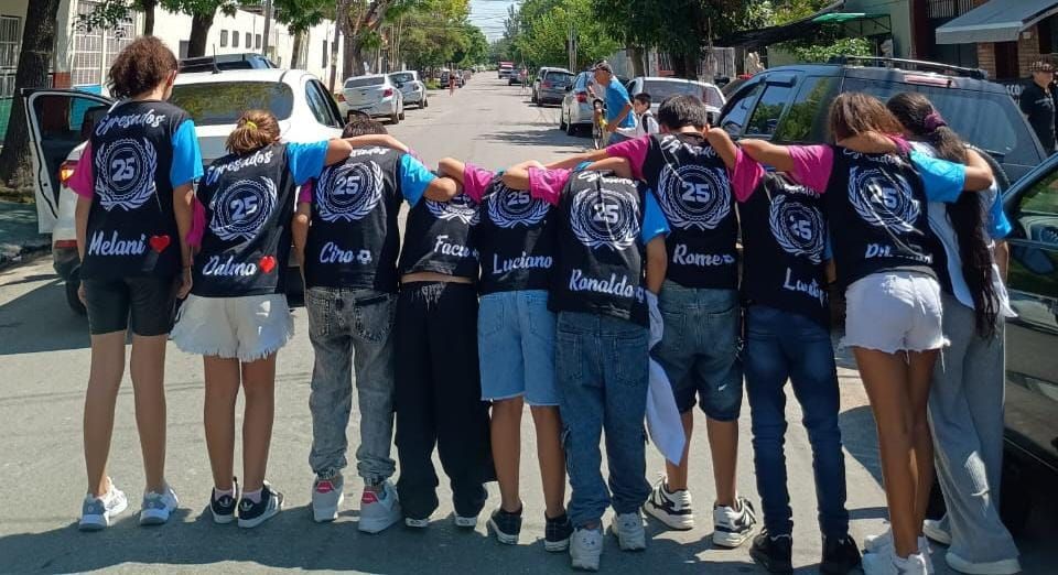 Un grupo de niños están parados en una calle con camisetas iguales.