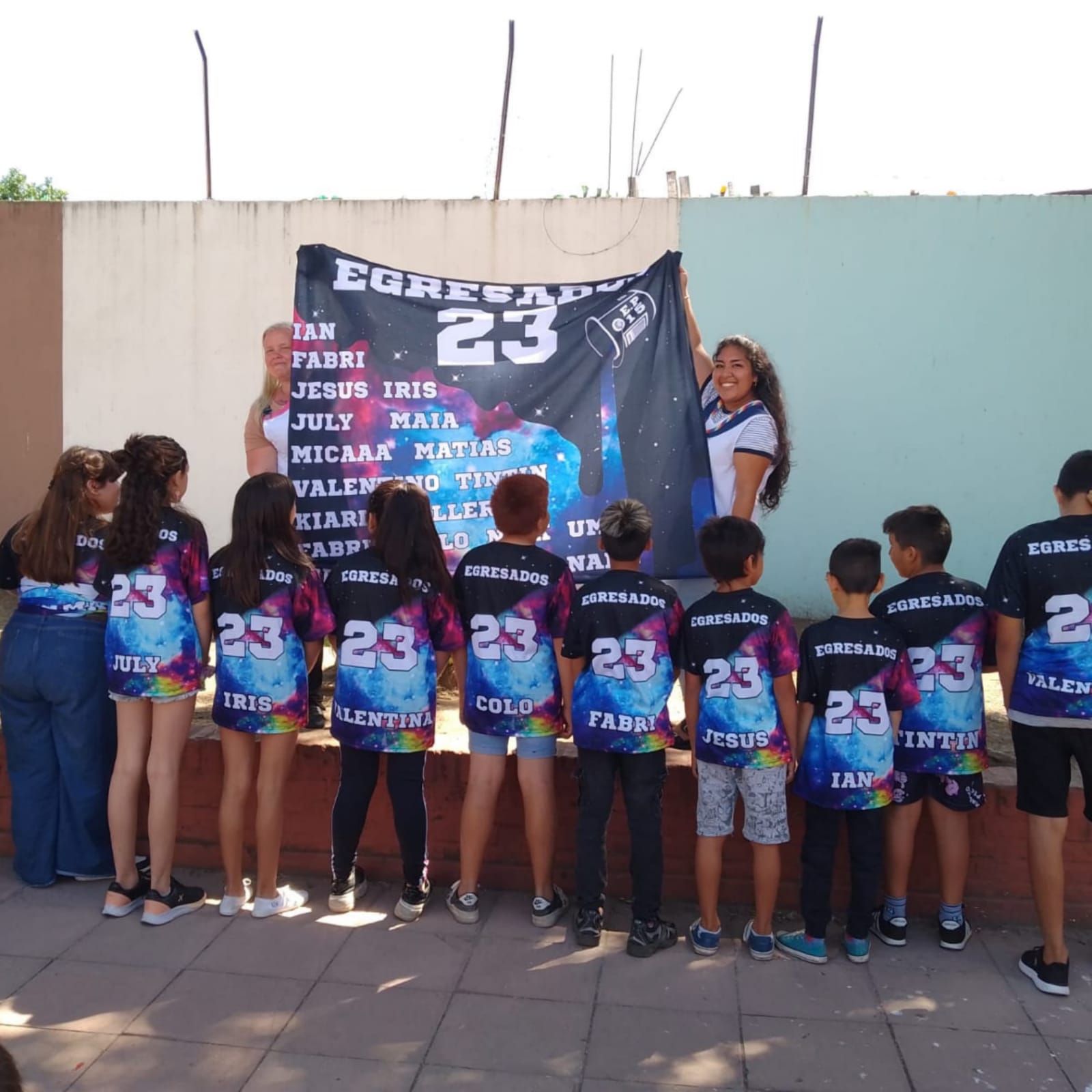 Un grupo de niños de pie frente a un cartel que dice 23