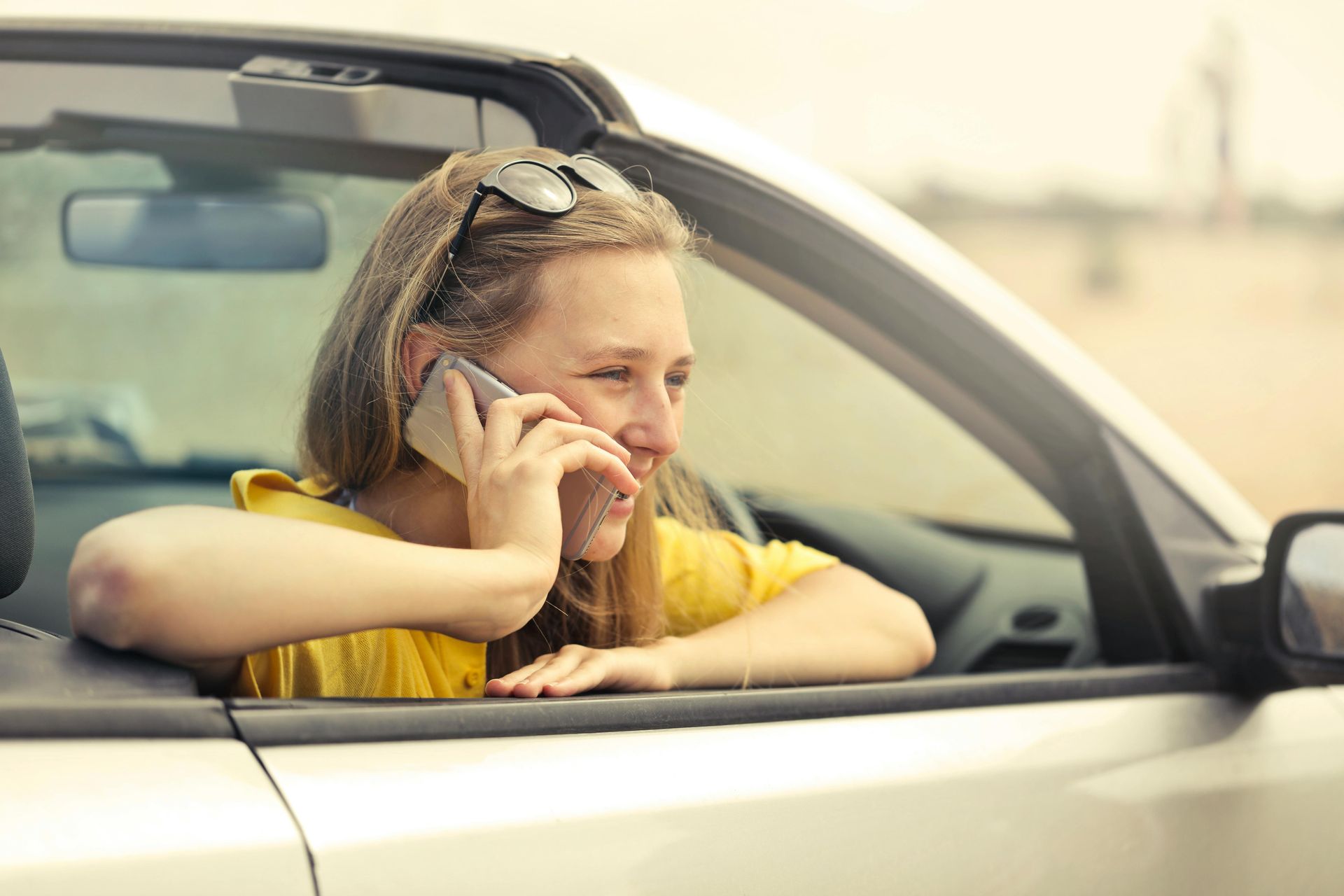 A woman is sitting in a car talking on a cell phone.
