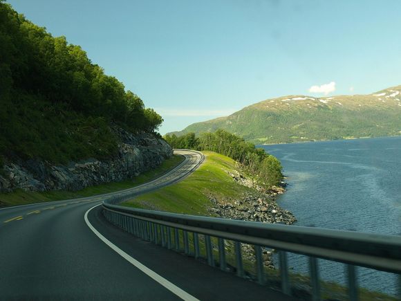 A road with a lake and mountains in the background