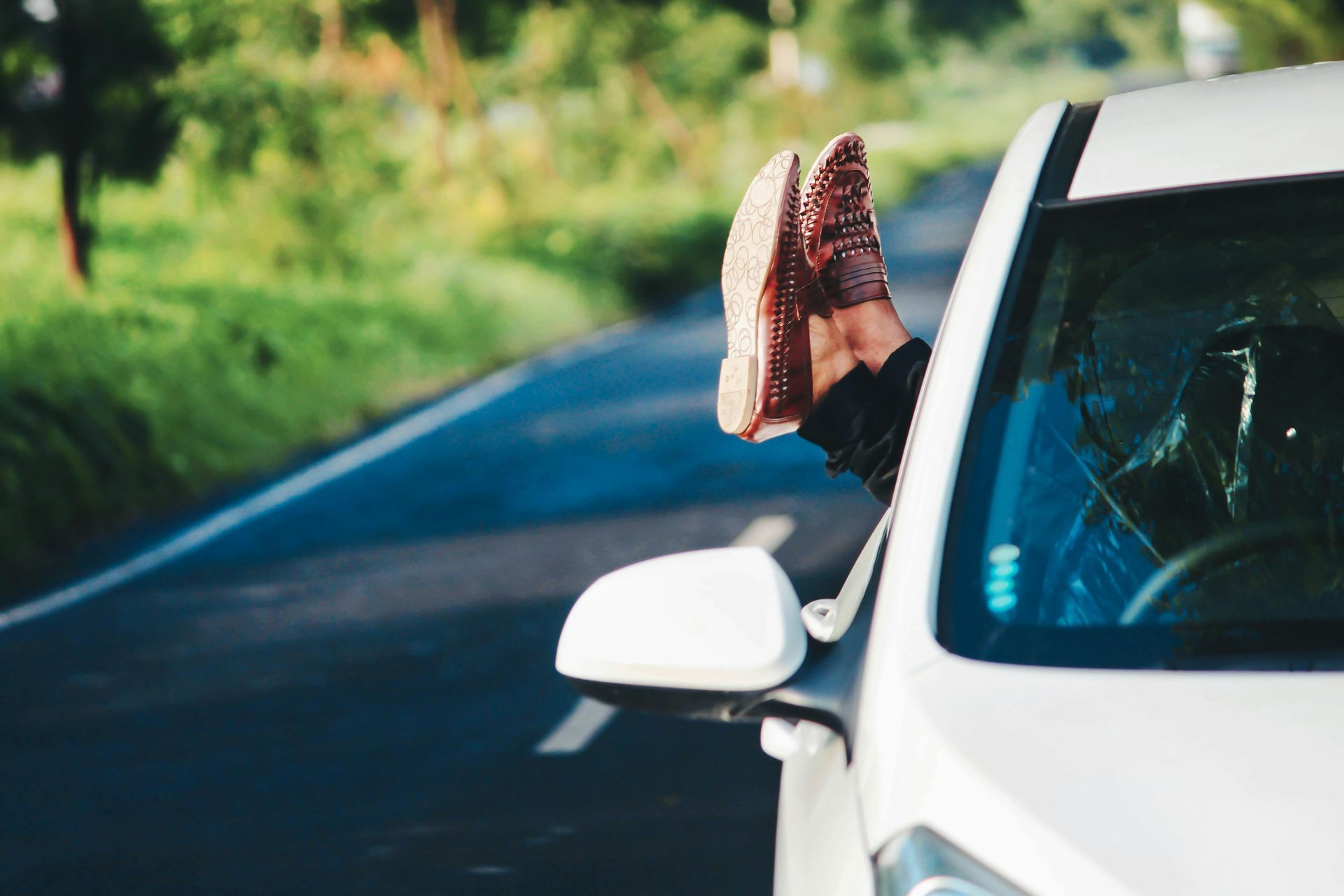 A person is sticking their feet out of the window of a car.
