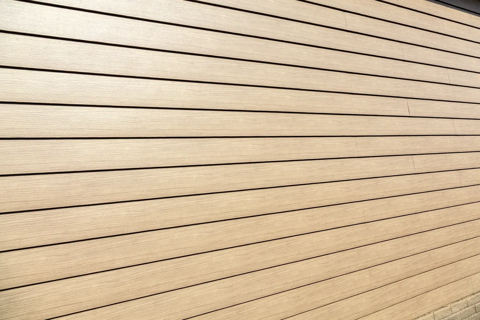 White bathtub with tiled walls in a bathroom, light brown floor, faucet on the side.