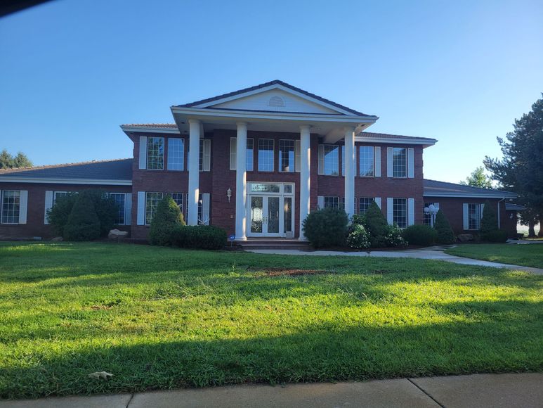 A large brick house with a lush green lawn in front of it