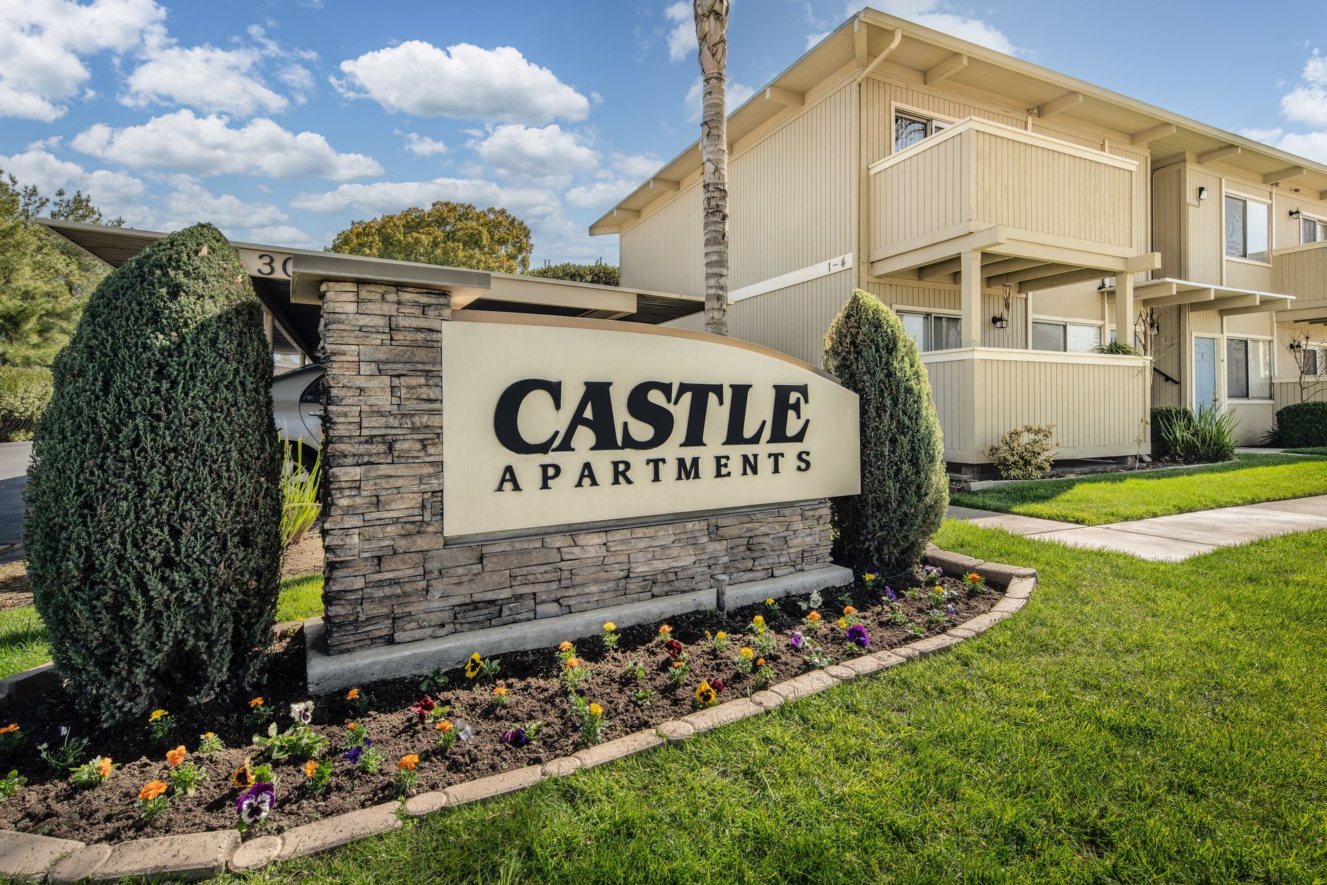 Castle Apartments sign with building and landscaping.