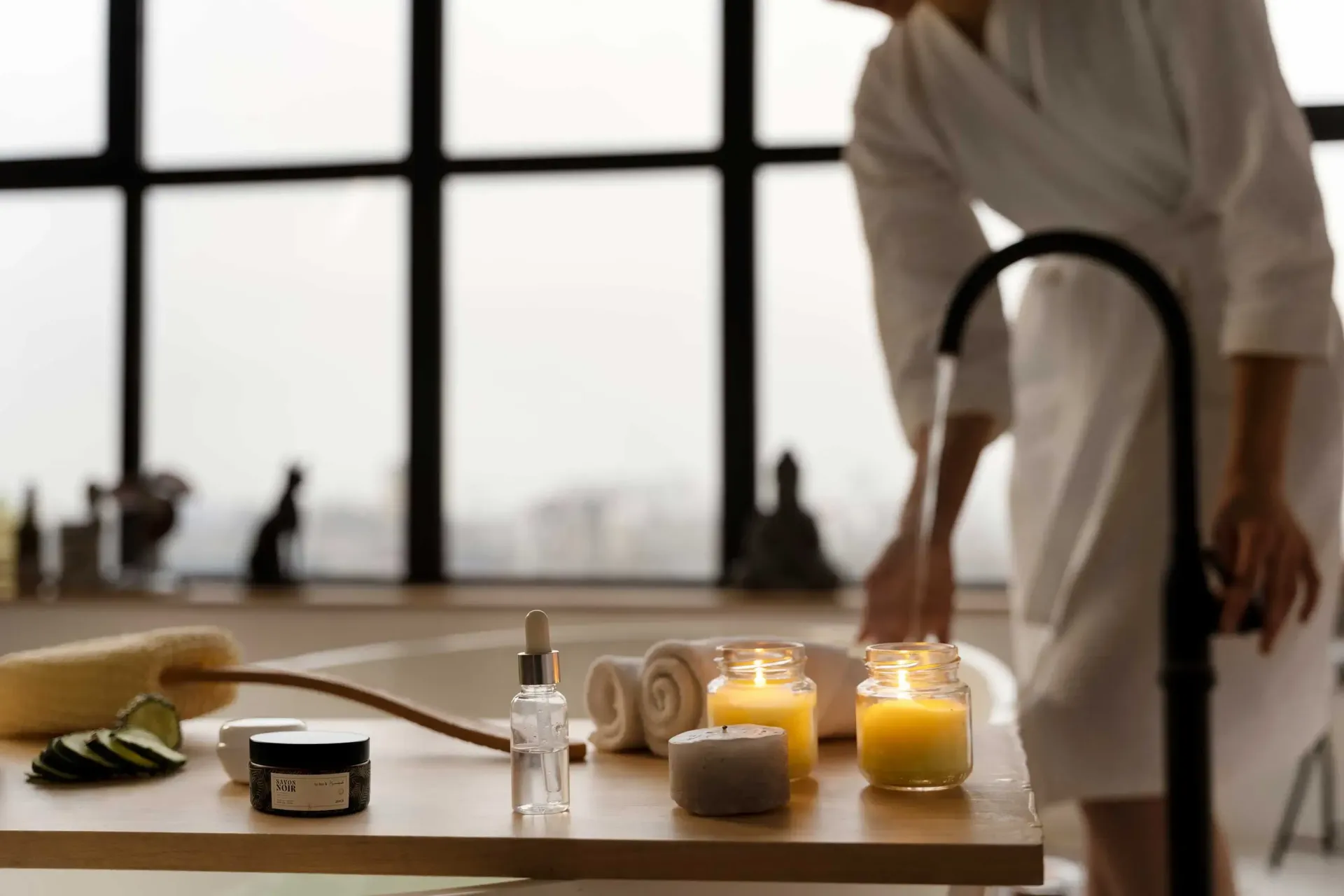 Candlelit spa bathroom with a freestanding tub, soft towels, and warm glowing candles all around