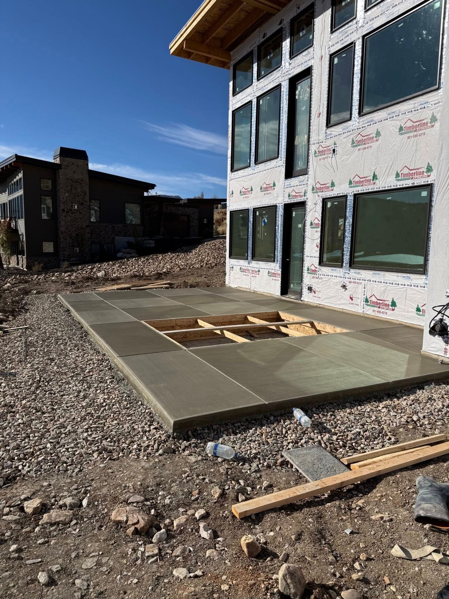 A newly poured concrete patio with a recessed center area at a modern home under construction.