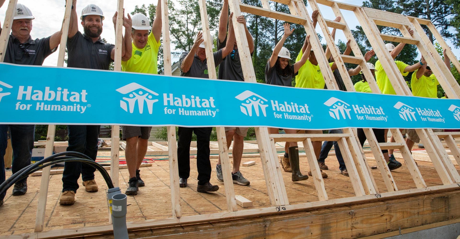 A group of people are standing in front of a habitat for humanity sign