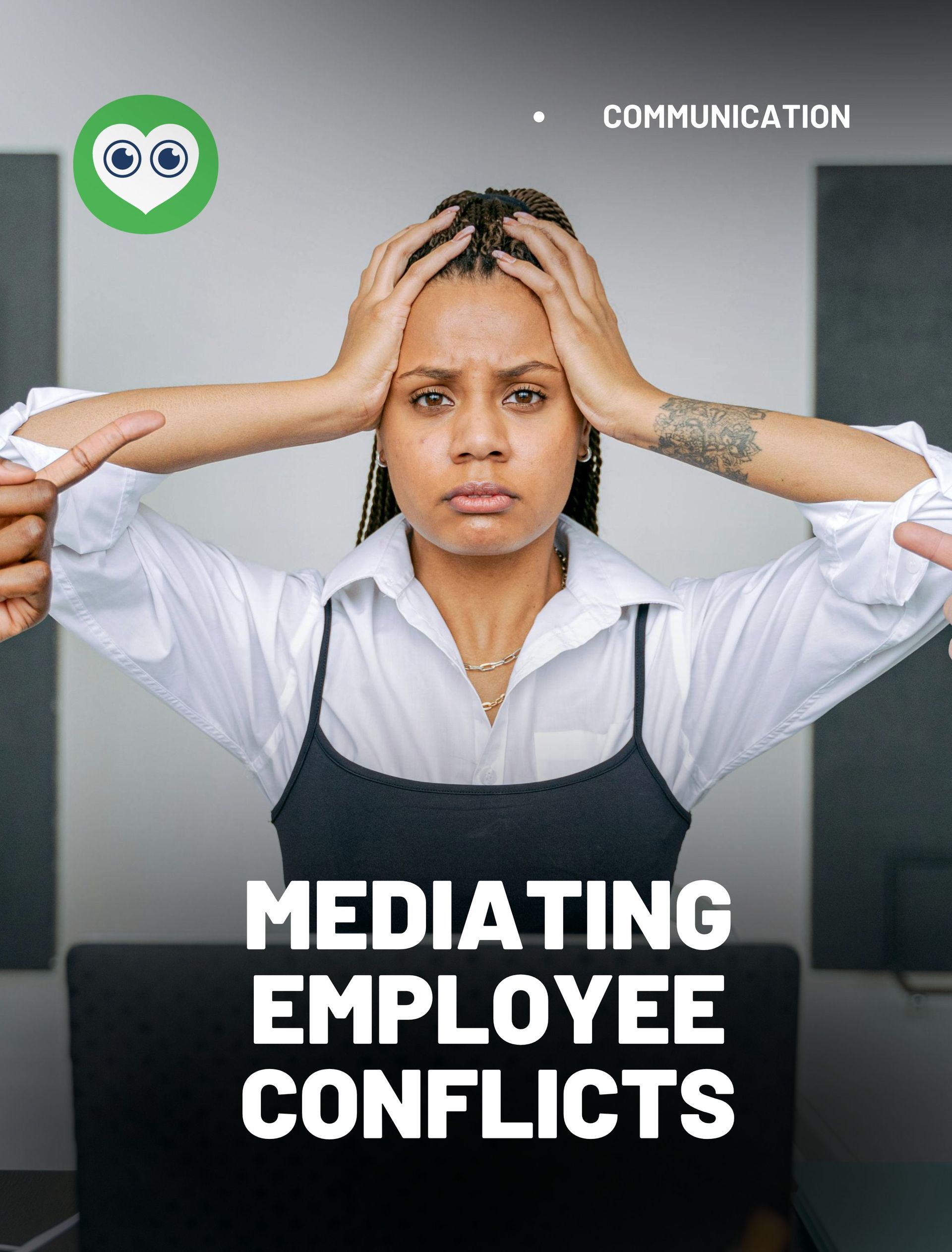 A woman is sitting at a desk with her hands on her head.