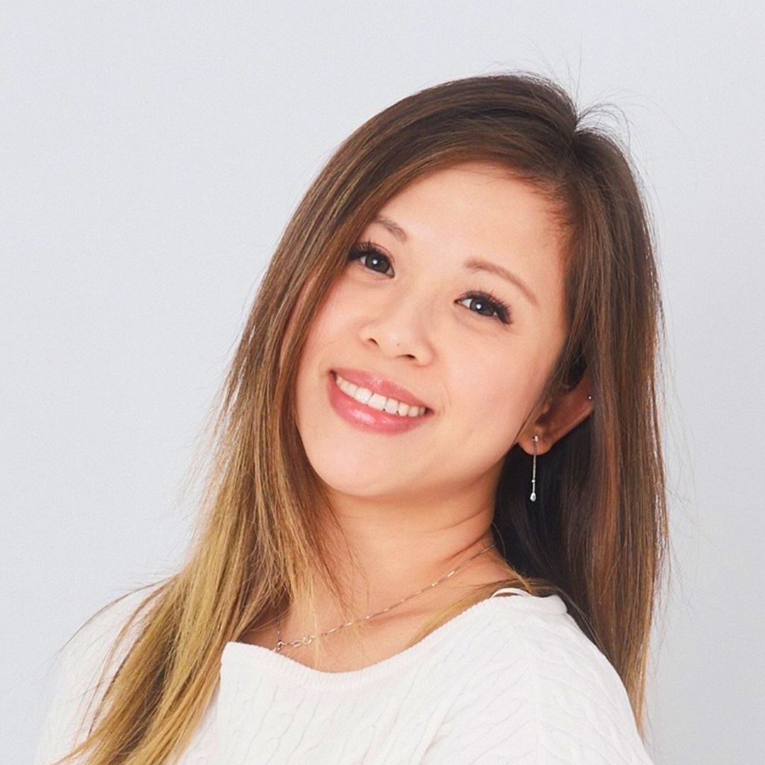 A woman with long hair is smiling and wearing a white shirt