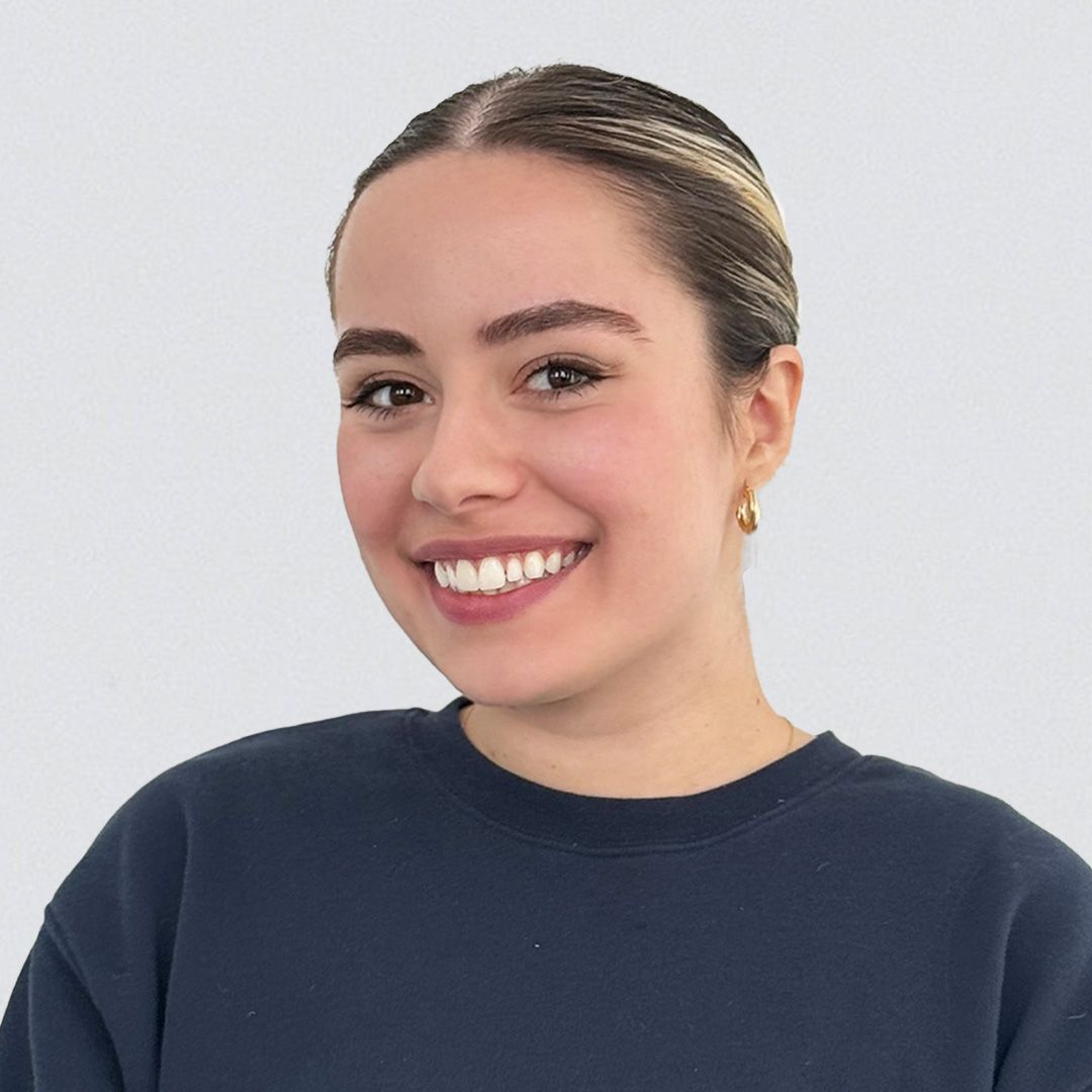 A woman in a blue sweater is smiling for the camera.