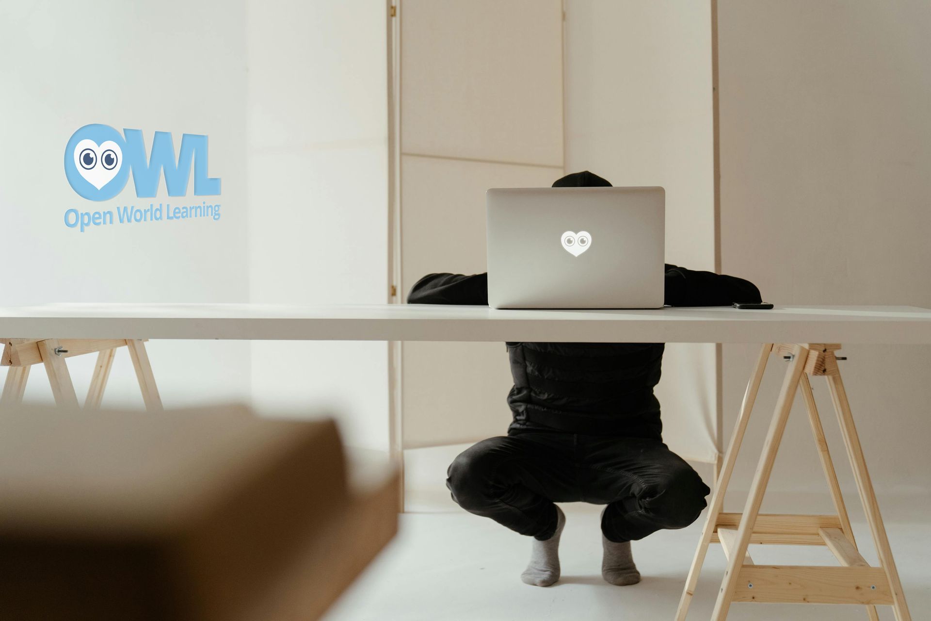 Two women are sitting at a table looking at a laptop computer.