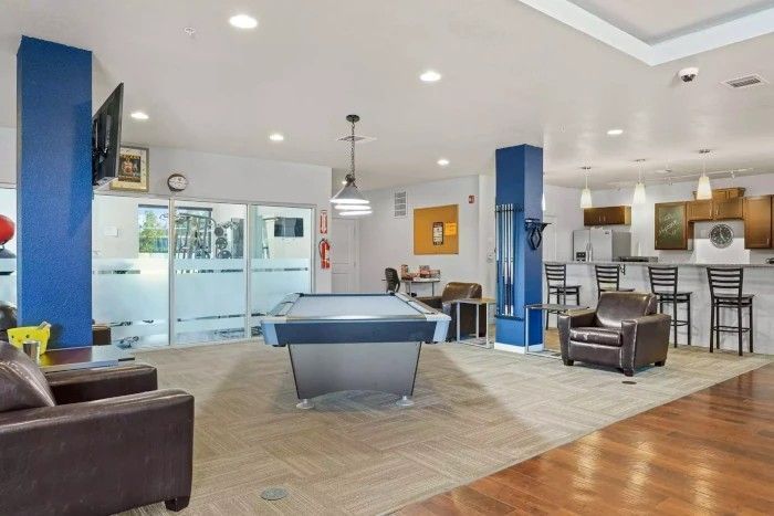 Spacious modern game room with a pool table, seating, and a kitchen bar area