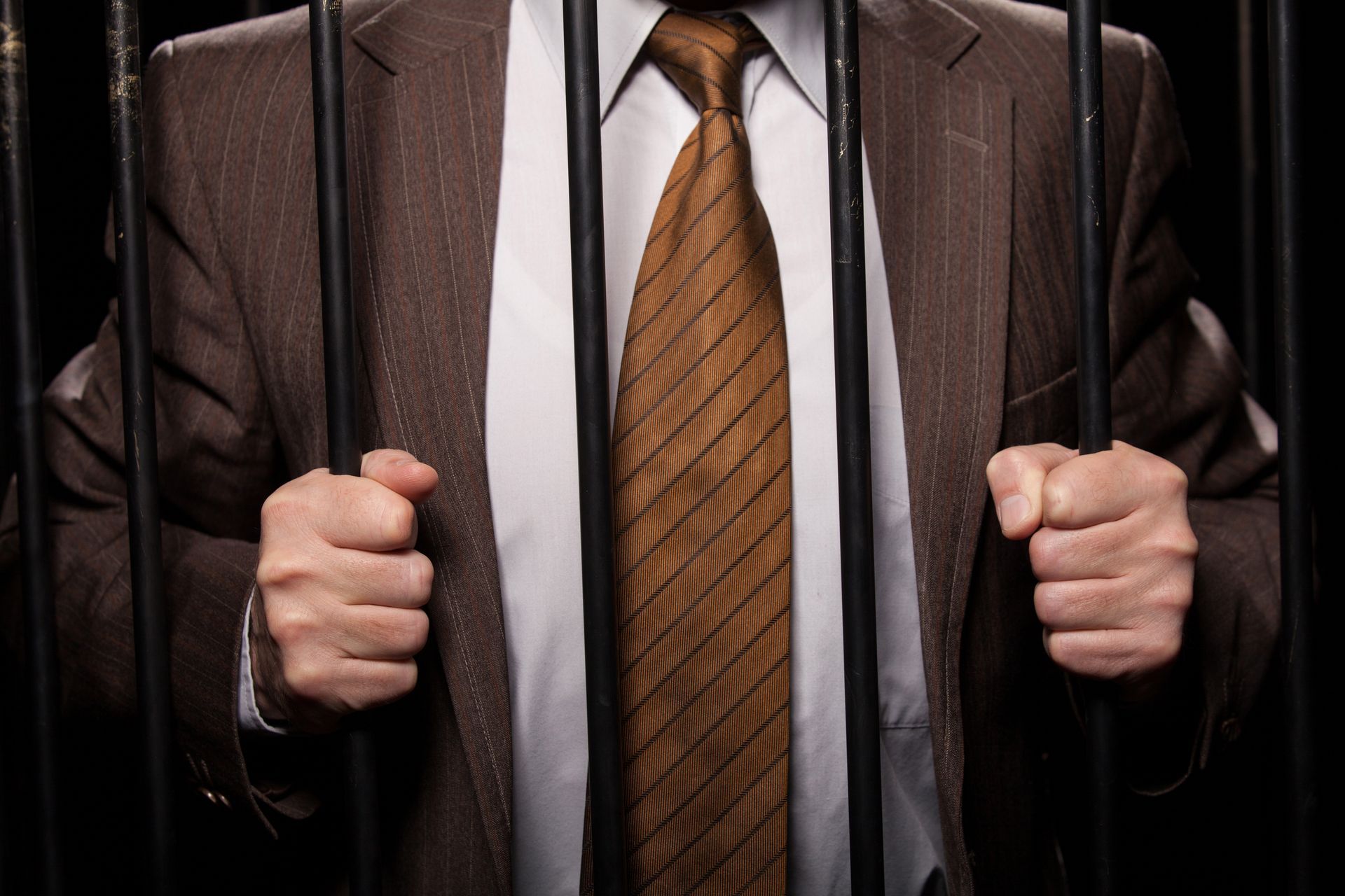 A man in a suit and tie is behind bars.