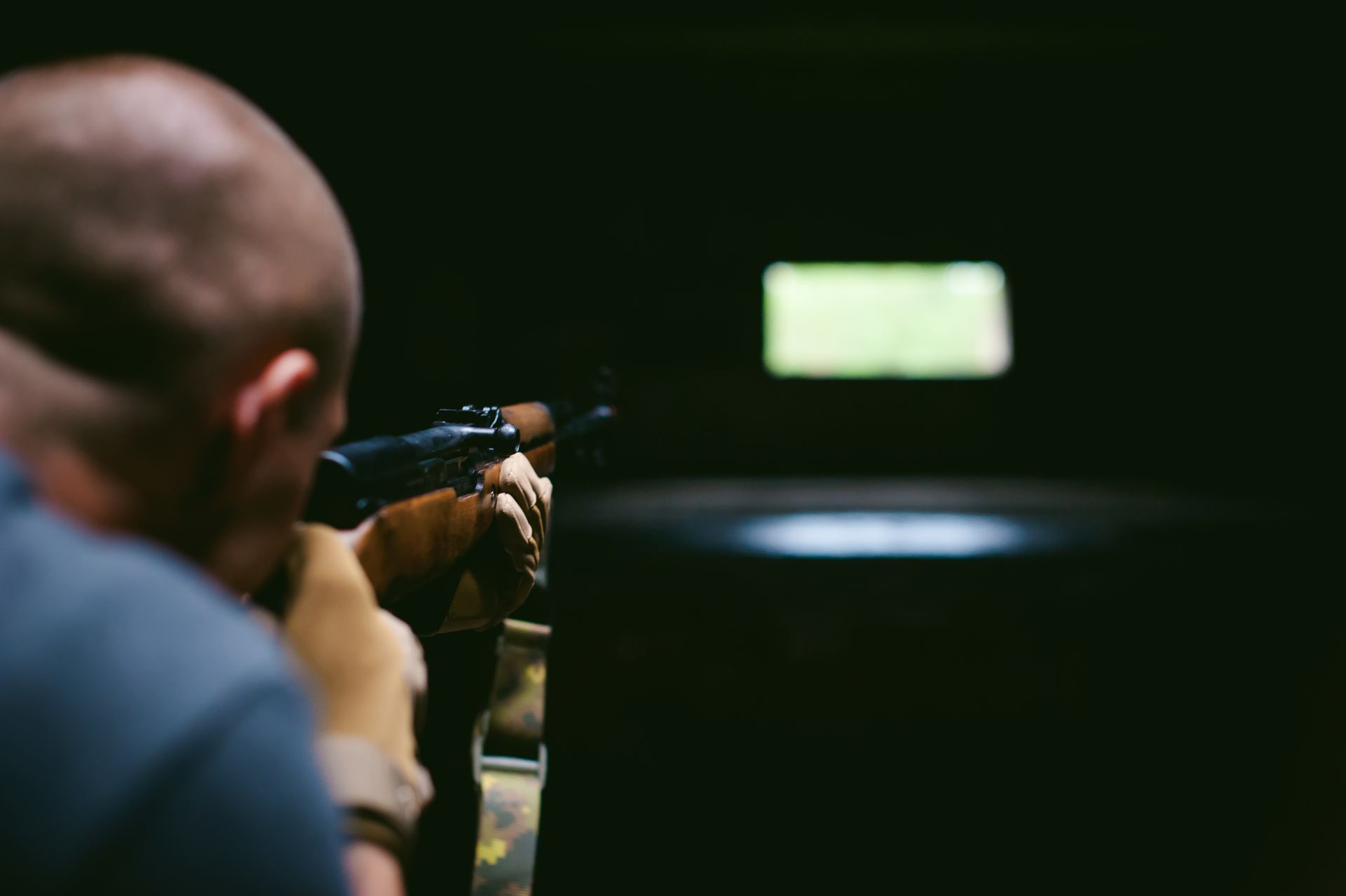 Man aiming a rifle at a target in a dim indoor shooting range, representing gun charges in Chicago.