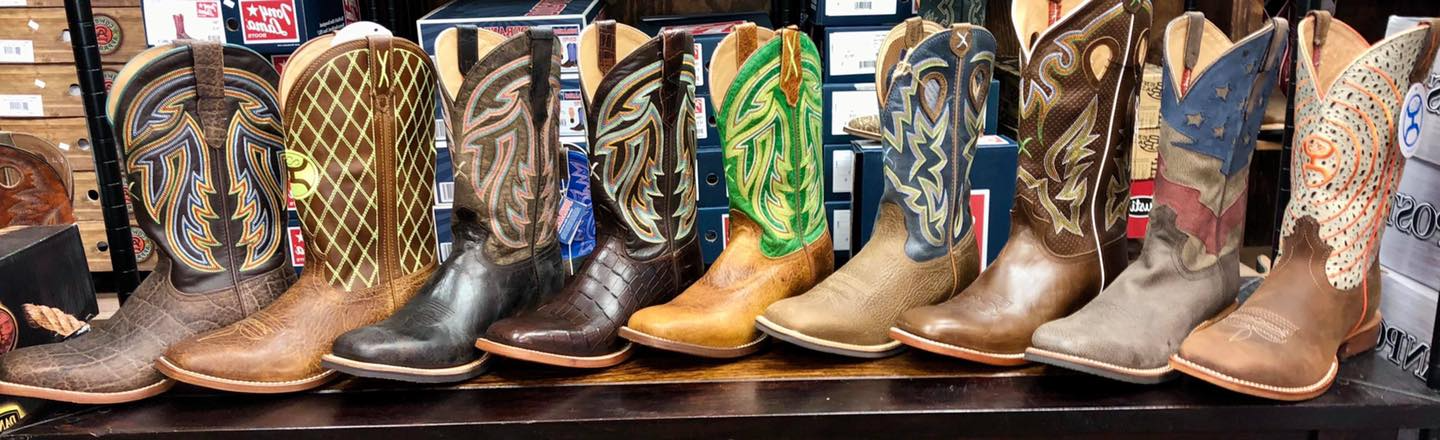 A row of cowboy boots are lined up on a shelf in a store.