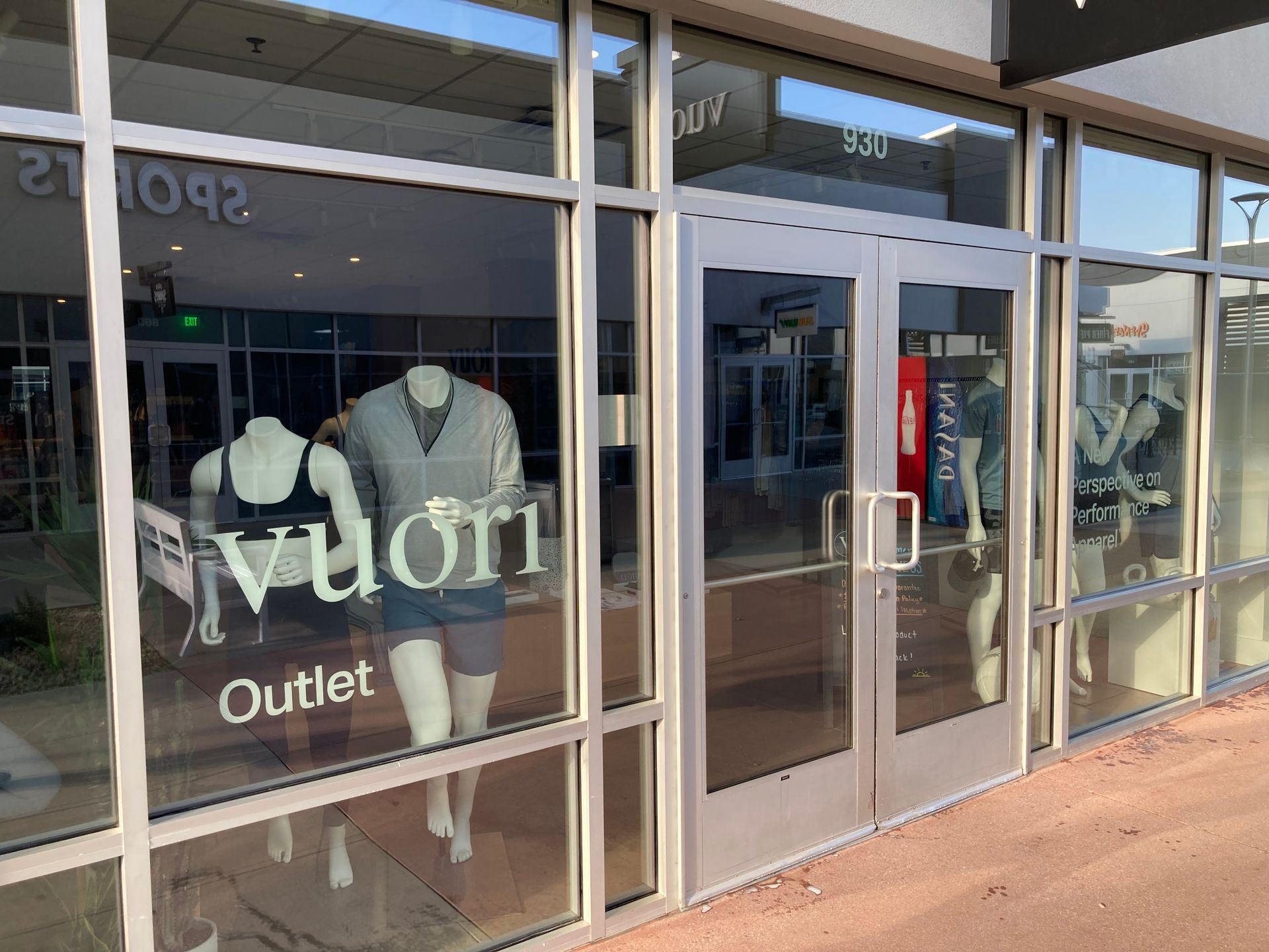 Storefront of a Vuori Outlet shop with clothing mannequins displayed in the window.