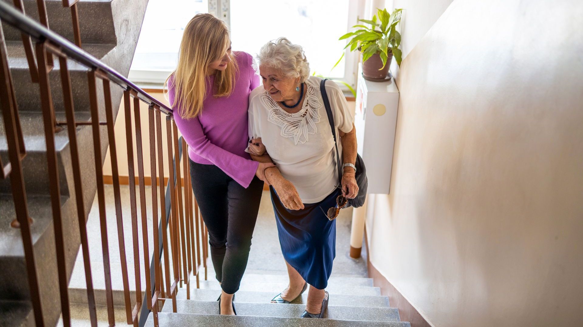 Une femme aide une femme âgée à monter les escaliers.