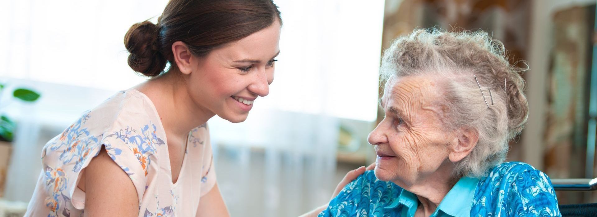 Une jeune femme parle à une femme plus âgée dans un salon.