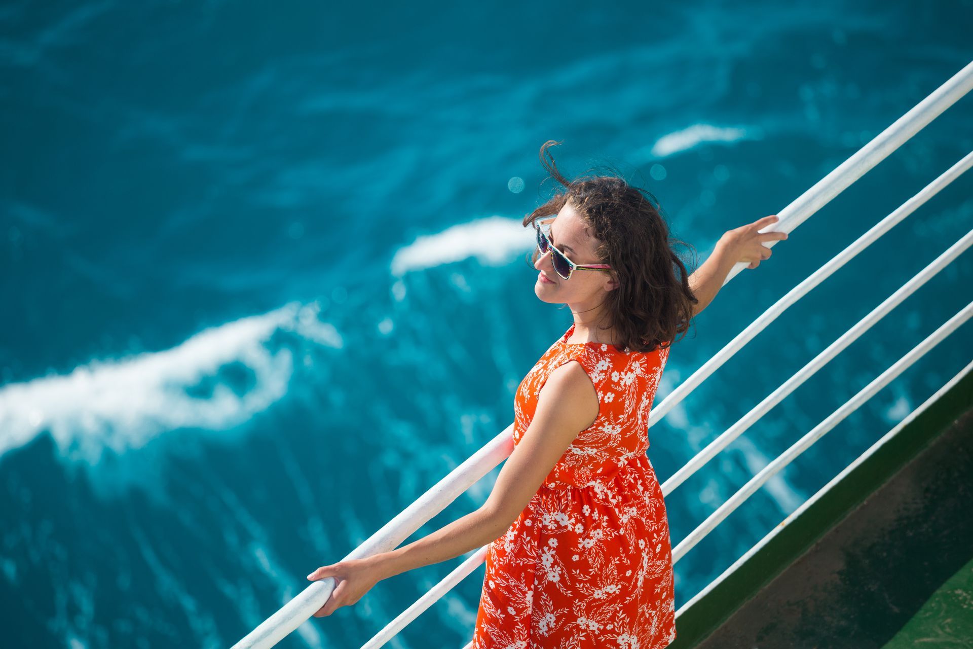 A woman in an orange dress is standing on the deck of a cruise ship.
