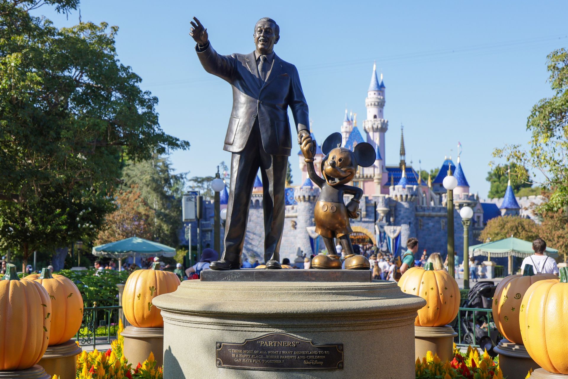 A statue of walt disney and mickey mouse in front of a castle