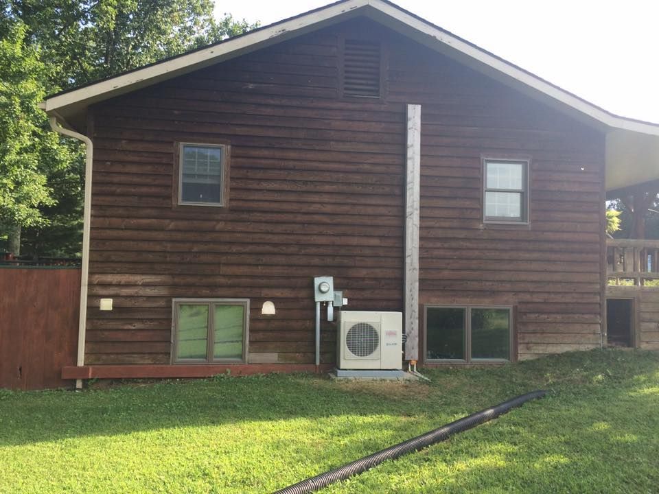 A large brown house with a lot of windows is sitting on top of a lush green hillside.