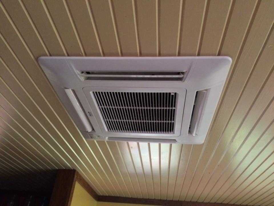 A square air conditioner is hanging from the ceiling of a room.