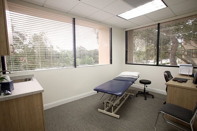 A doctor 's office with a blue table and a desk.