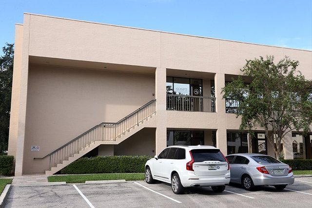 Two cars are parked in front of a building with stairs.