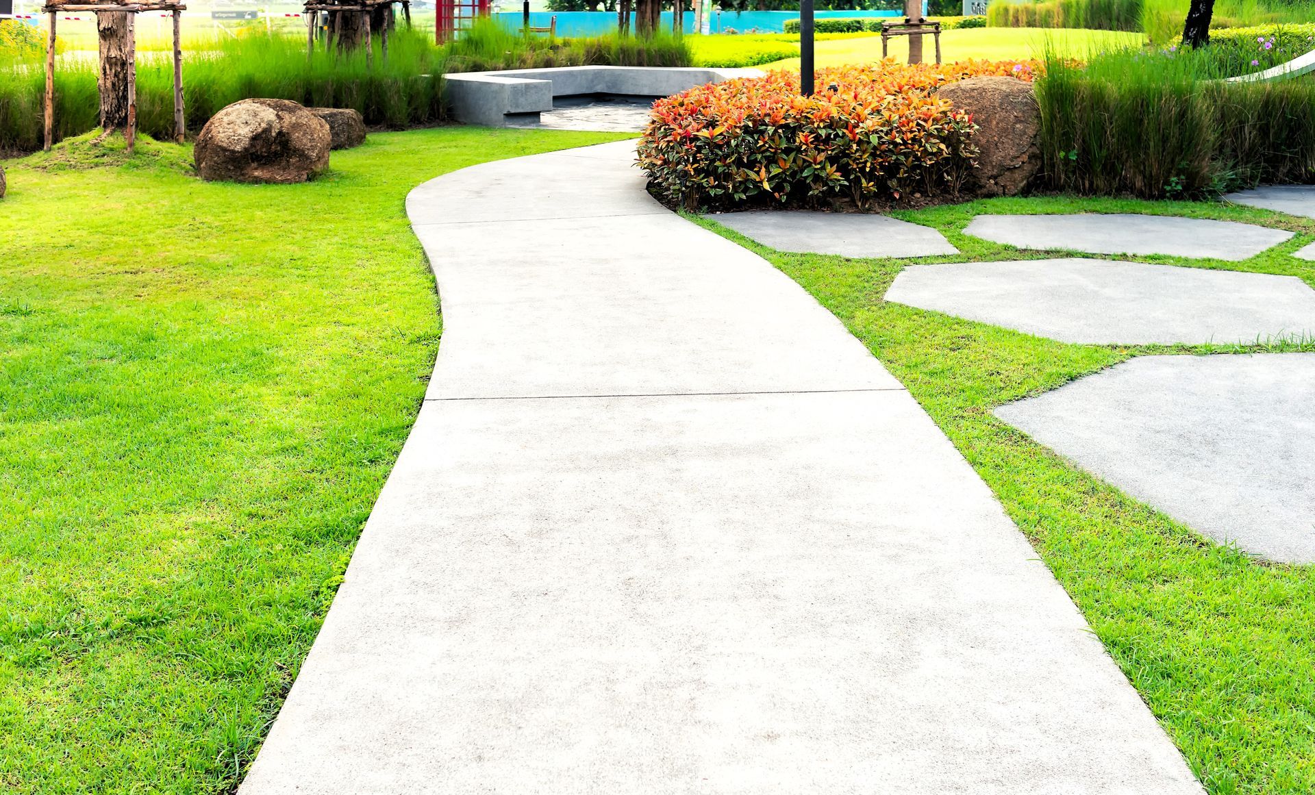 Concrete walkway surrounded by lush greenery and bushes in the garden