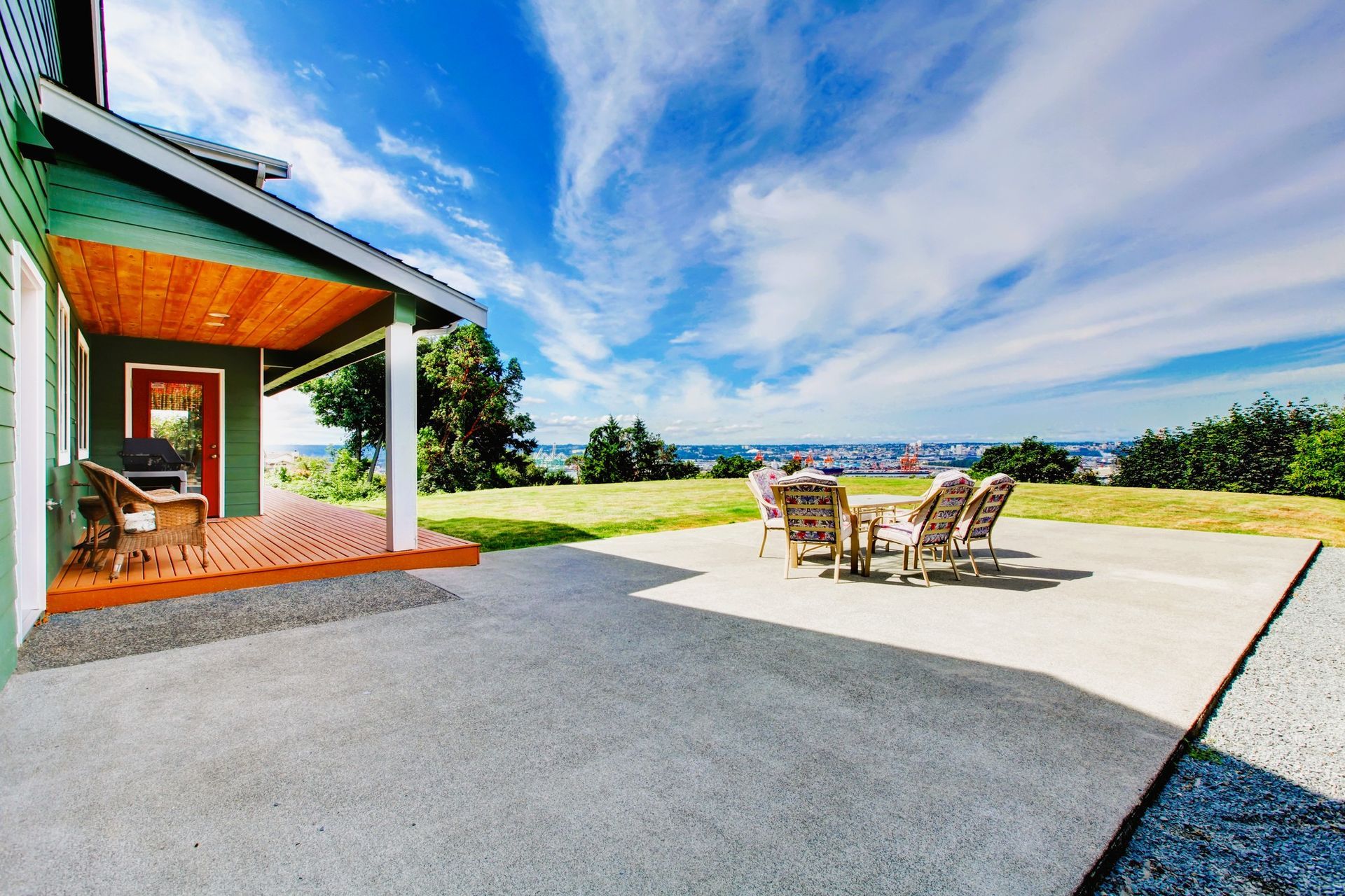 Spacious concrete patio with a dining set overlooking a scenic view under a clear blue sky.