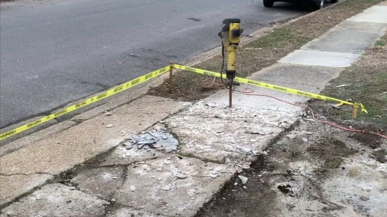 Concrete sidewalk repair with jackhammer and caution tape