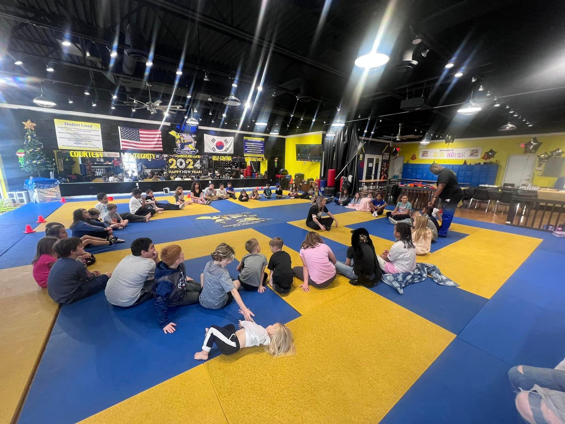 A group of children are sitting on the floor in a gym.