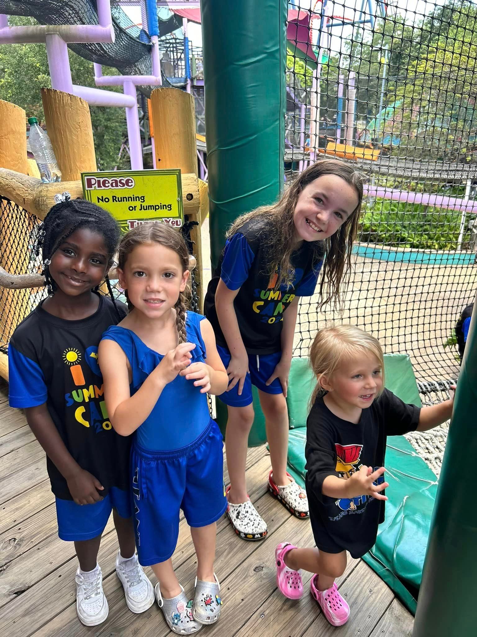 A group of young girls are standing next to each other at a playground.