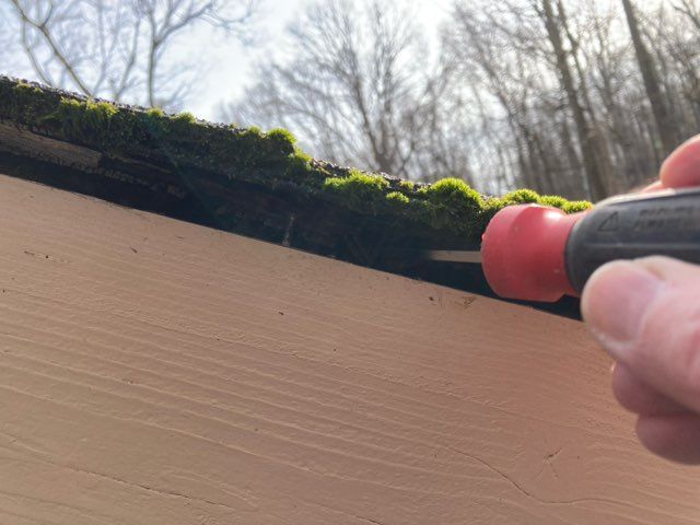 Probing roof sheathing to determine whether rot has occurred due to a lack of drip edge flashing.